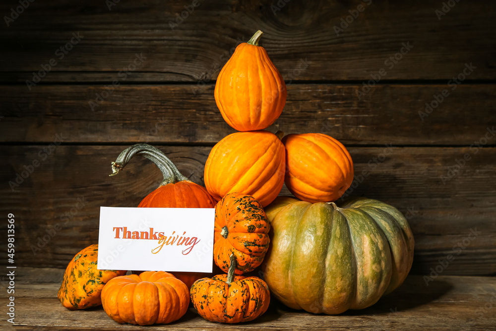 Different pumpkins and text THANKSGIVING on wooden background