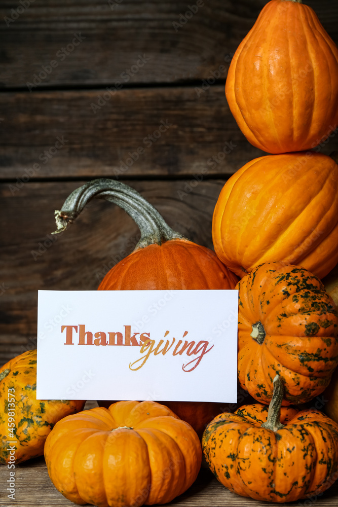 Different pumpkins and text THANKSGIVING on wooden background