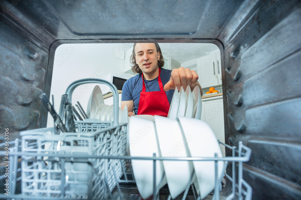 Man take out plates from the dishwasher machine