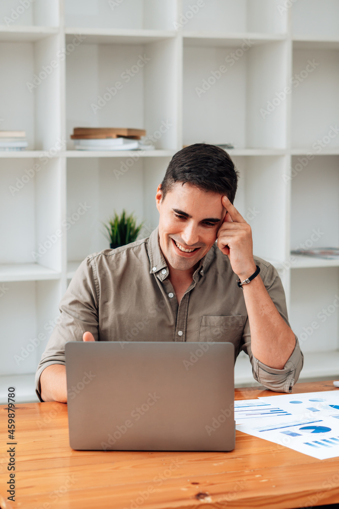 Handsome businessman in modern office looking on laptop