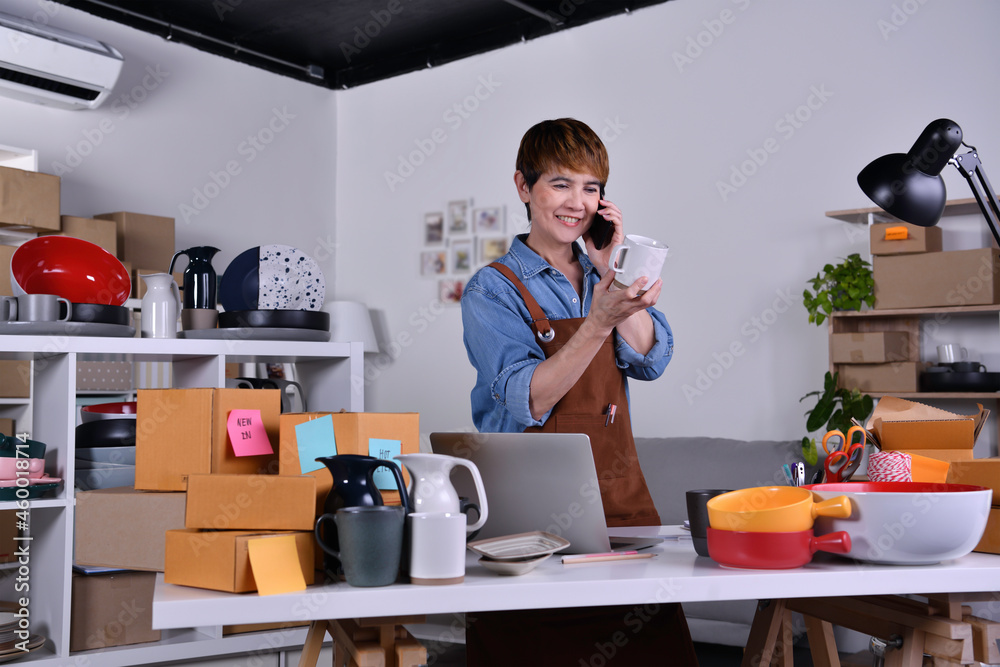 Mature Asian woman entrepreneur, Business owner checking product and talking to customer on the phon