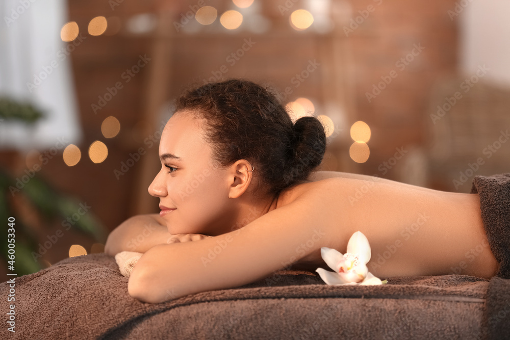 Beautiful young African-American woman relaxing in spa salon