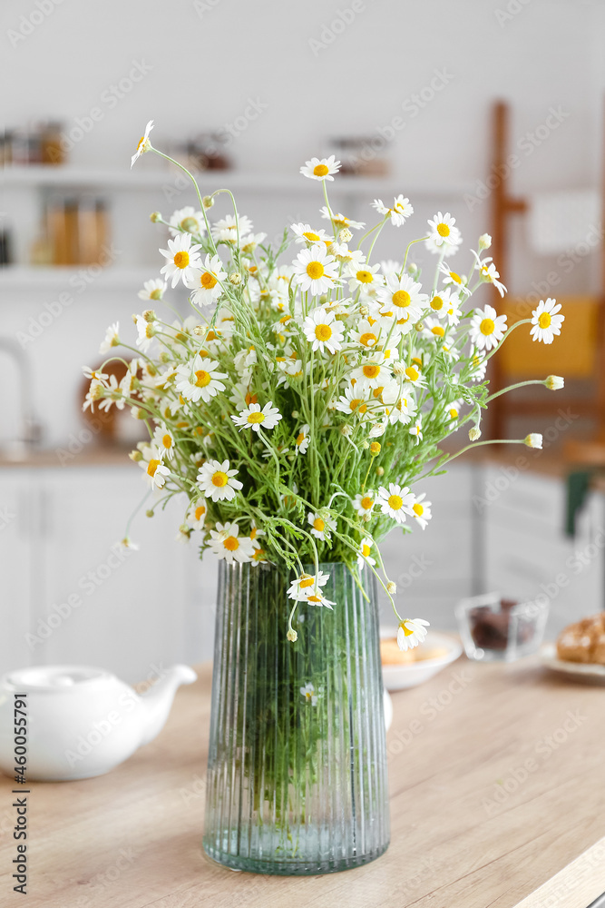 Vase with chamomiles on table in kitchen