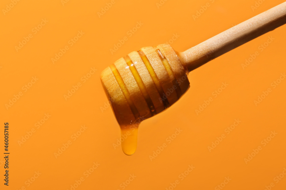 Sweet honey dripping from dipper on color background