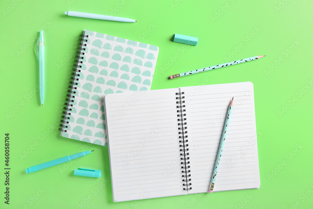 Notebooks, pens, pencils and eraser on color background