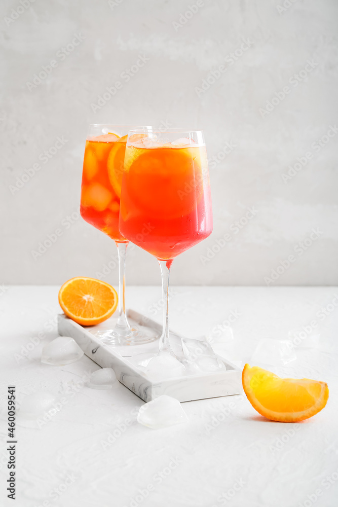 Glasses of Aperol spritz cocktail on light background