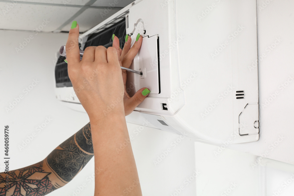 Female electrician repairing air conditioner in room, closeup