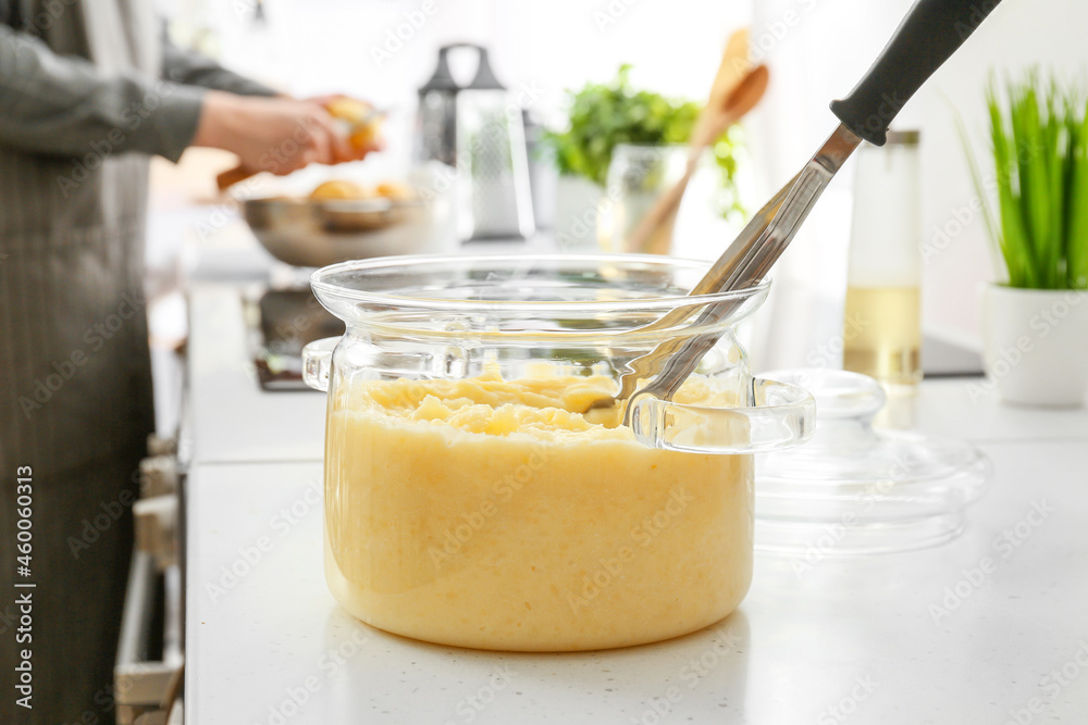 Pot with tasty mashed potatoes on table in kitchen