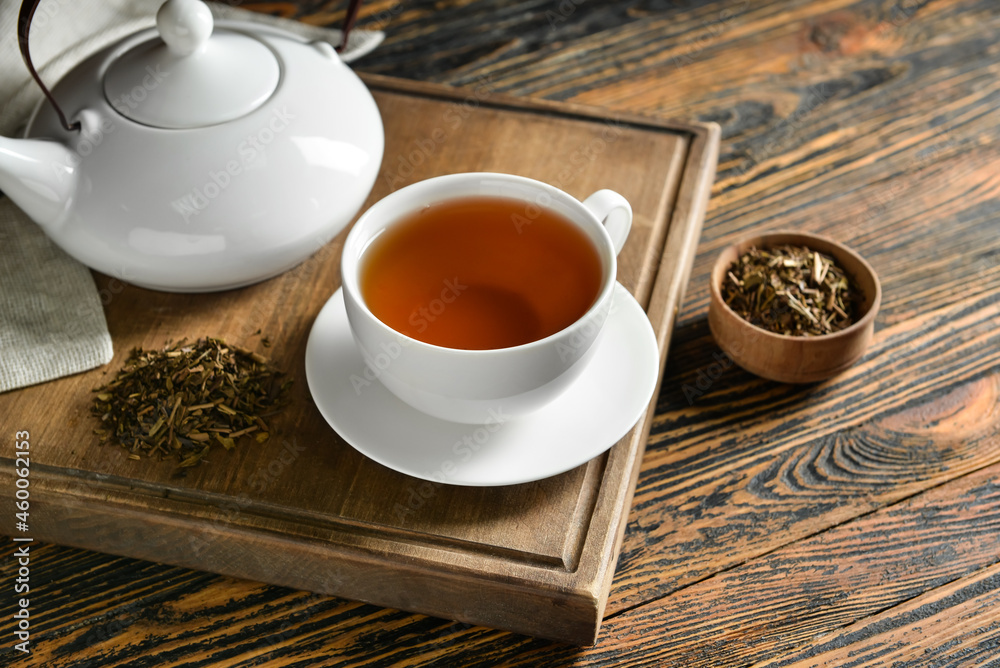 Composition with cup of tasty hojicha green tea on wooden background