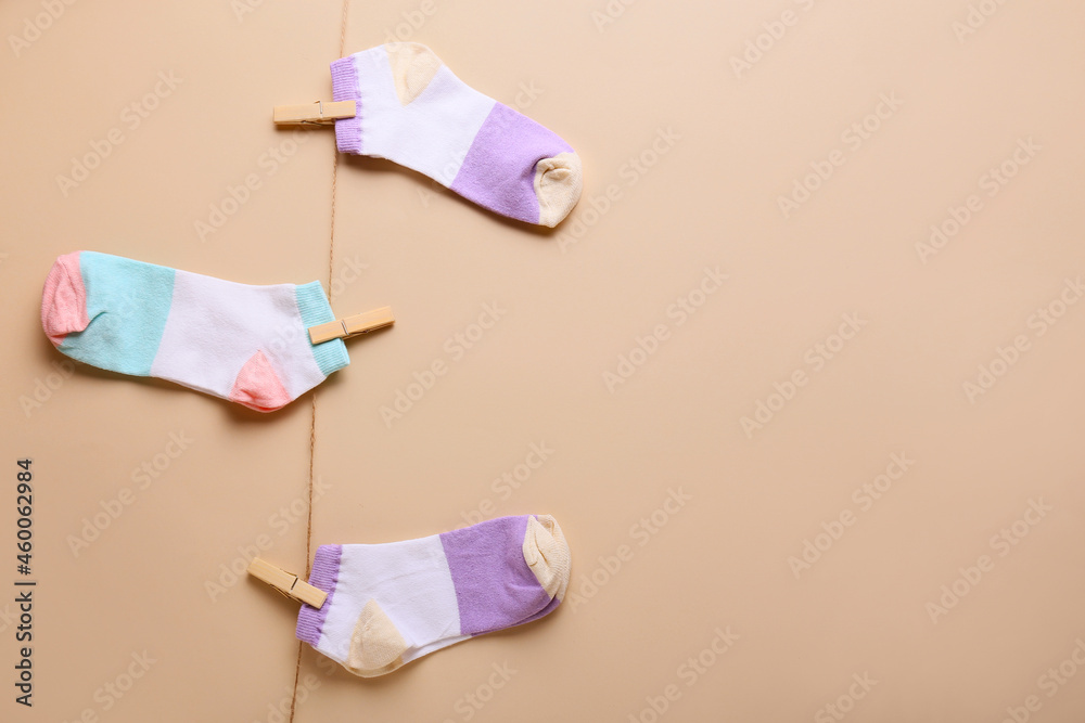 Different socks hanging on clothesline against color background