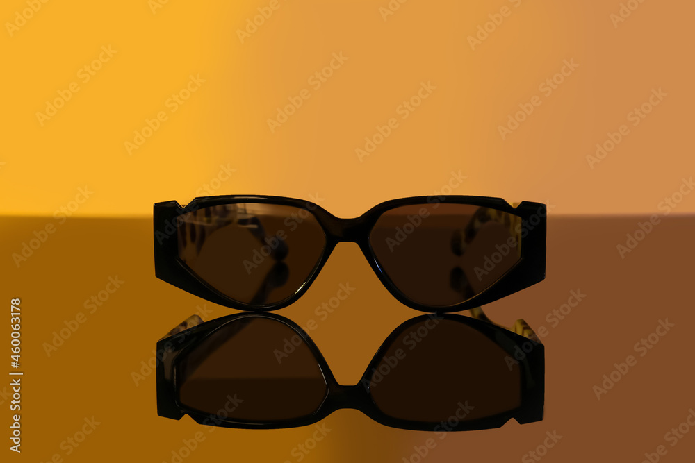 Stylish female sunglasses on color background