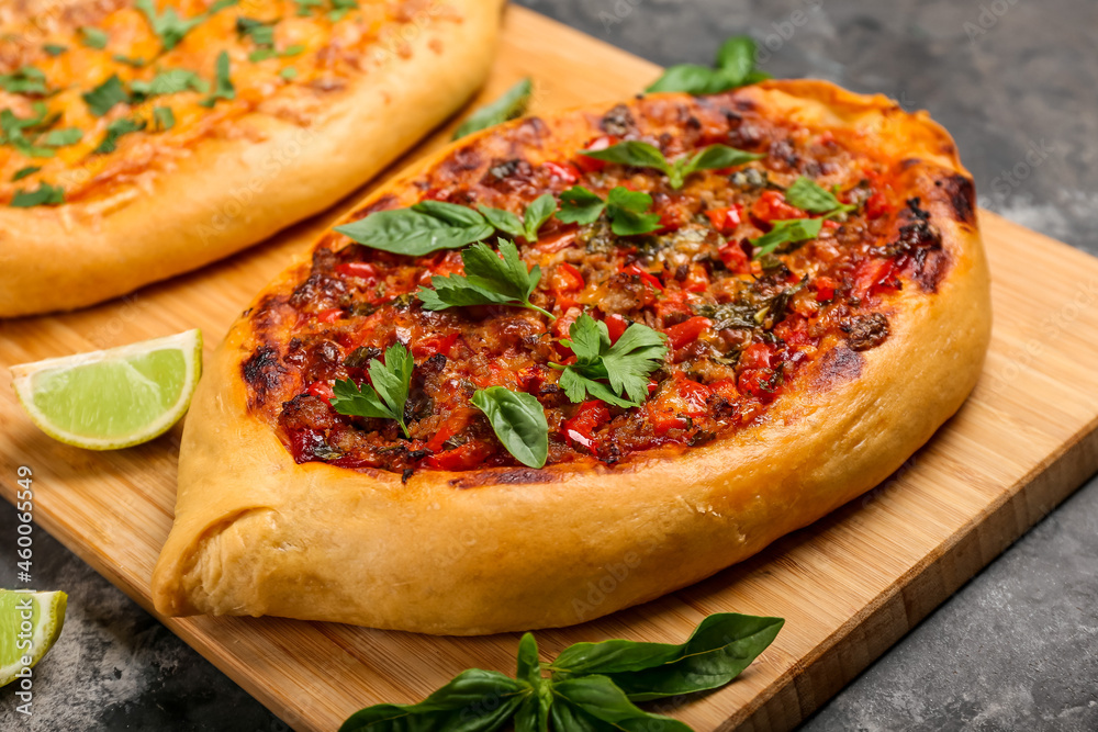 Wooden board with tasty Turkish Pizza on black background