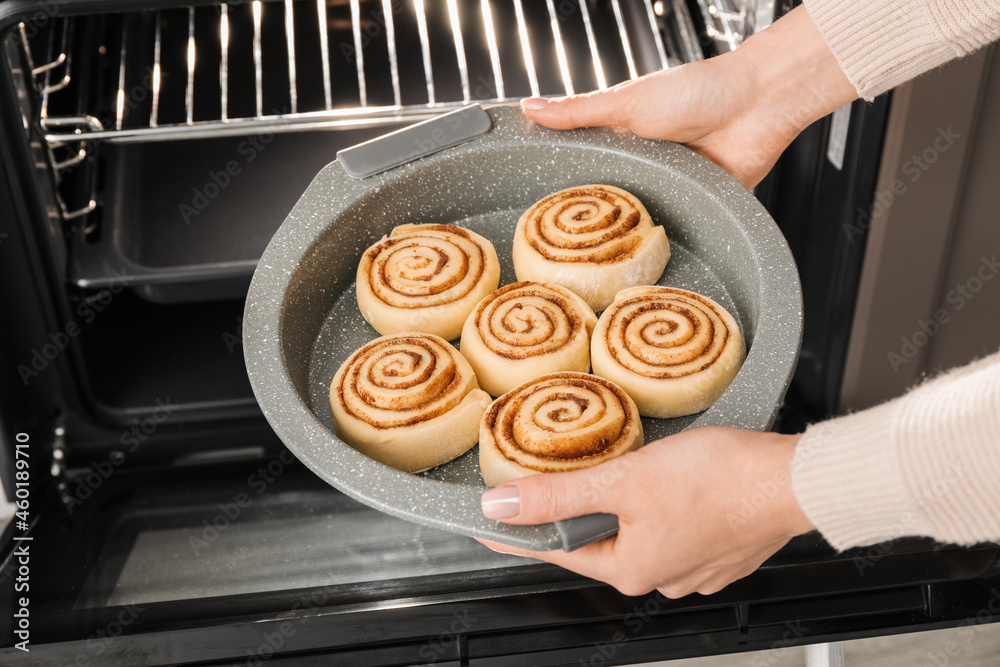 Woman putting uncooked cinnamon rolls in microwave oven