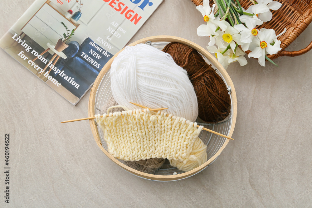 Basket with knitting yarn and needles on grey background