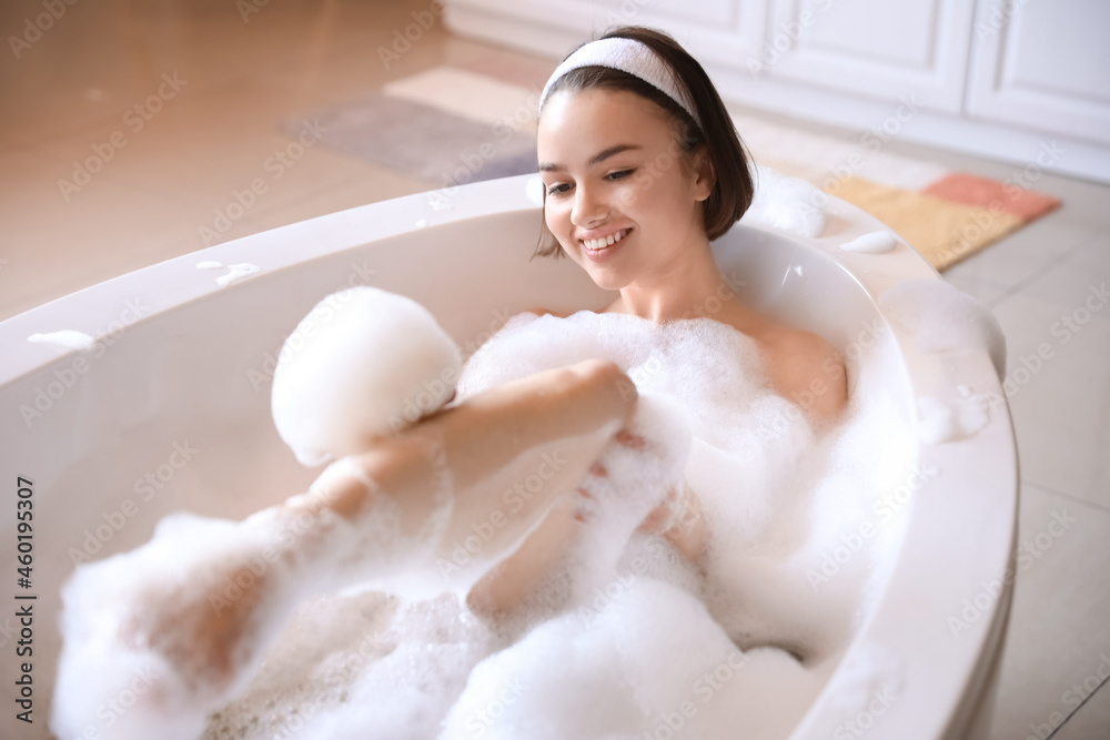 Young woman taking bath with foam at home