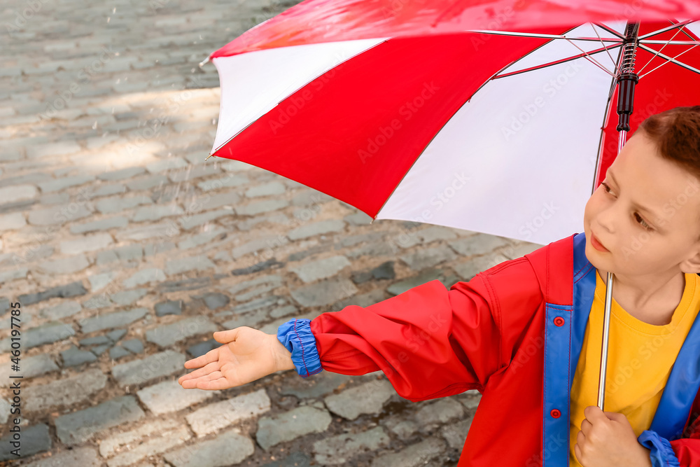 Cute little boy with umbrella outdoors on rainy day