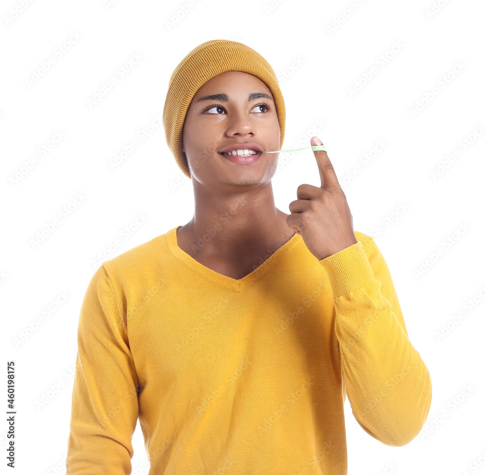 Happy African-American guy with chewing gum on white background