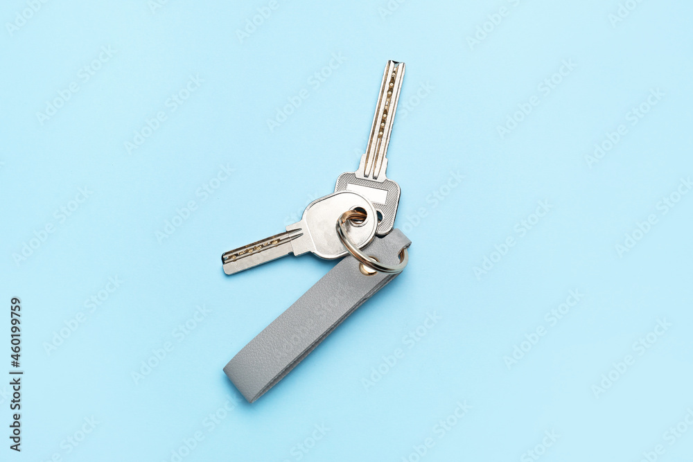 Keys with leather keychain on color background