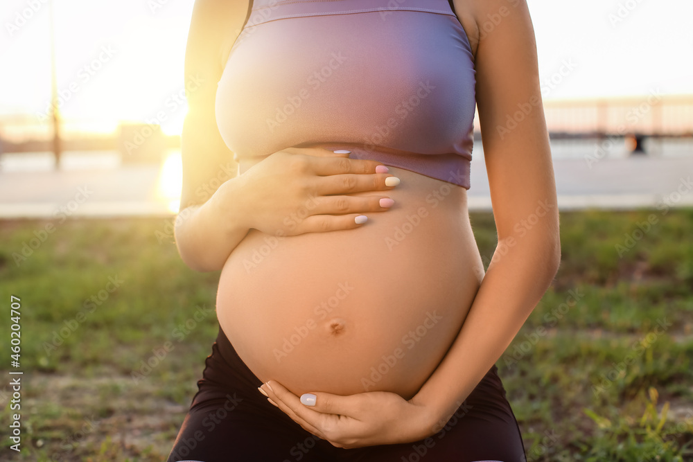 Young pregnant woman training in park, closeup