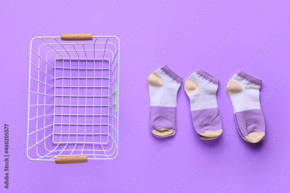 Basket with socks on lilac background