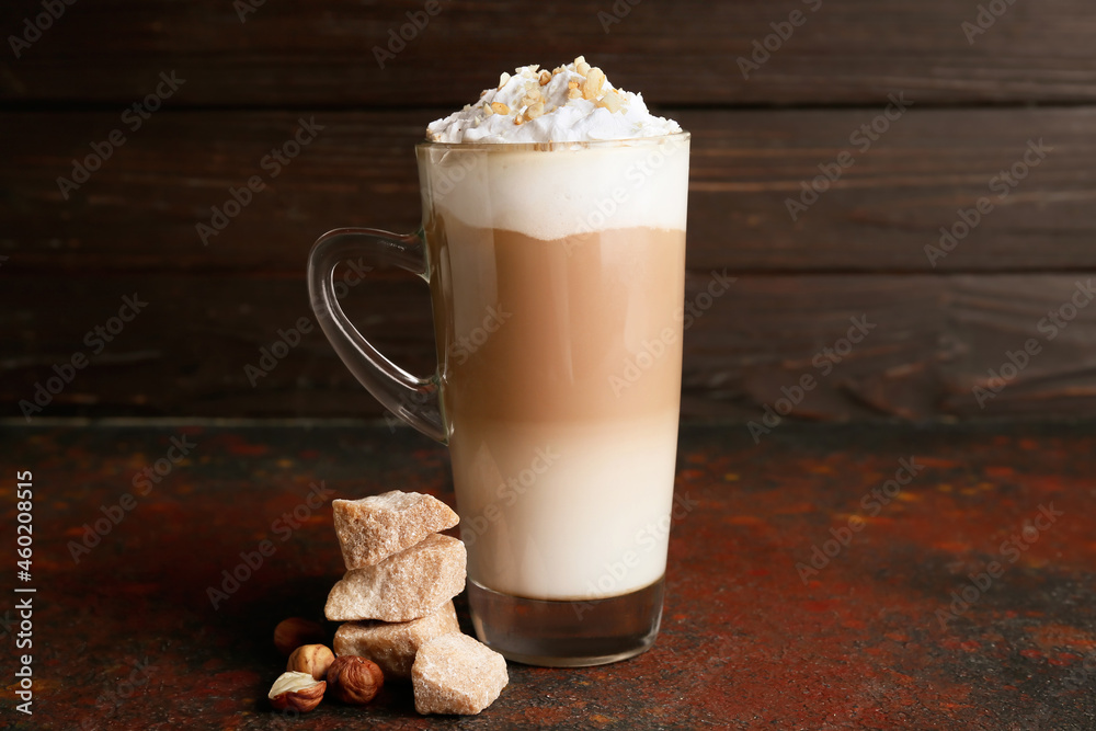 Glass cup of tasty latte with nuts on table