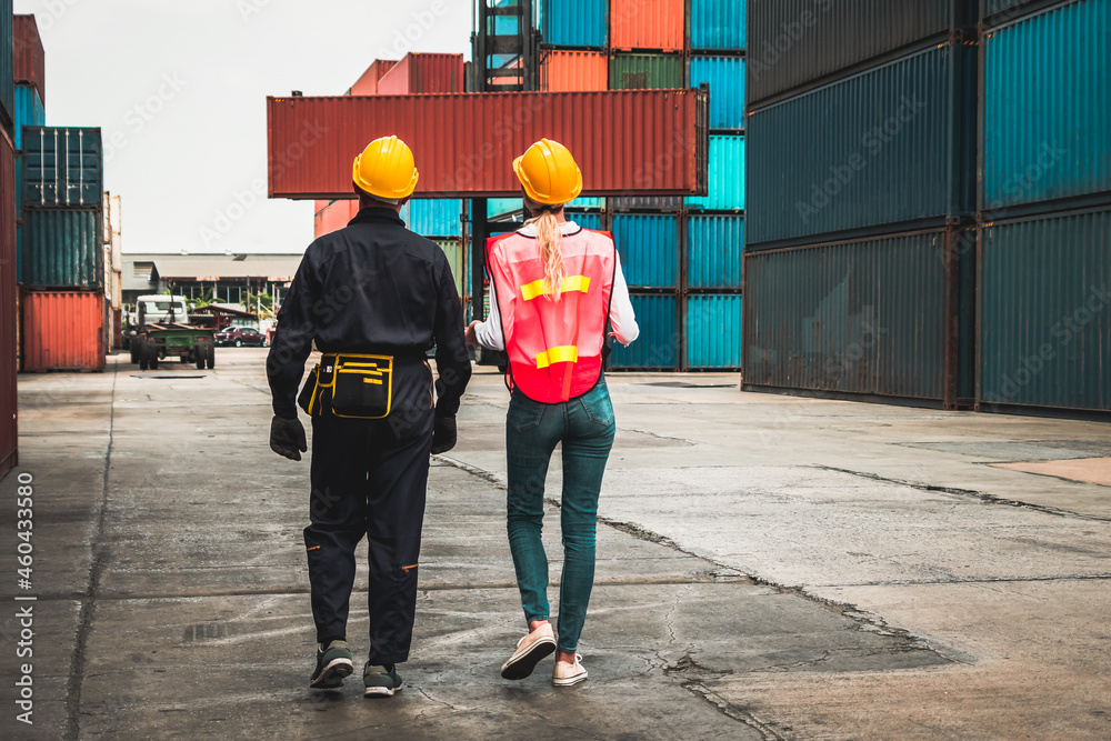 Industrial worker works with co-worker at overseas shipping container yard . Logistics supply chain 