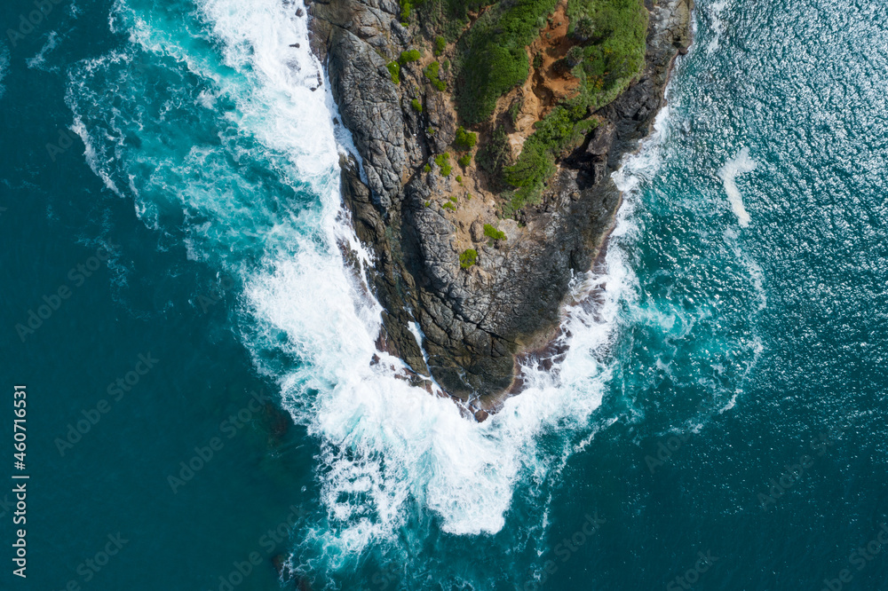 Aerial view Top down seashore big wave crashing on rock cliff Beautiful dark sea surface in sunny da