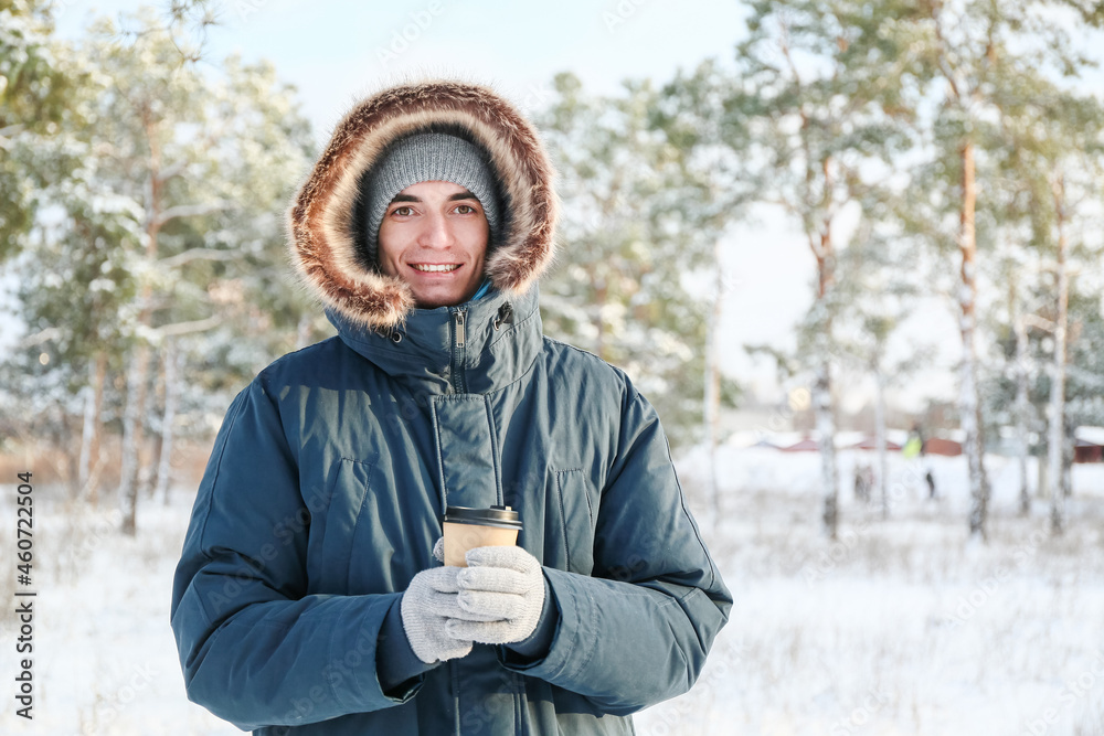 Young man with cup of hot tea on snowy day