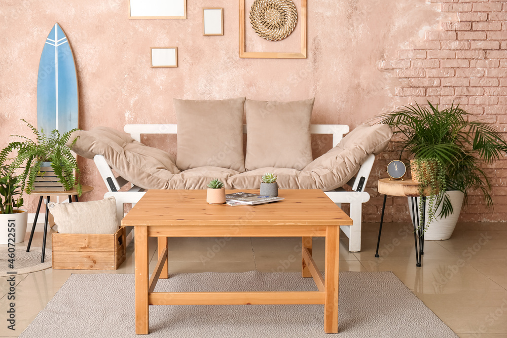 Interior of modern stylish room with surfboard, houseplants, table and sofa