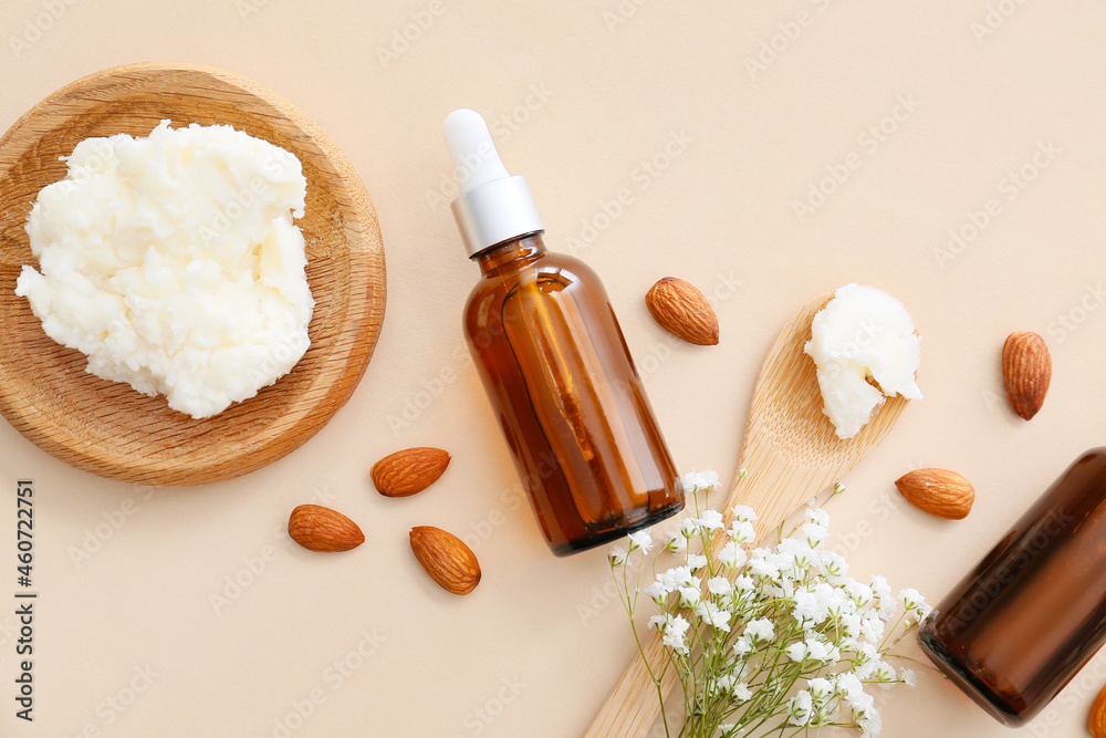 Bottles of almond essential oil on light background