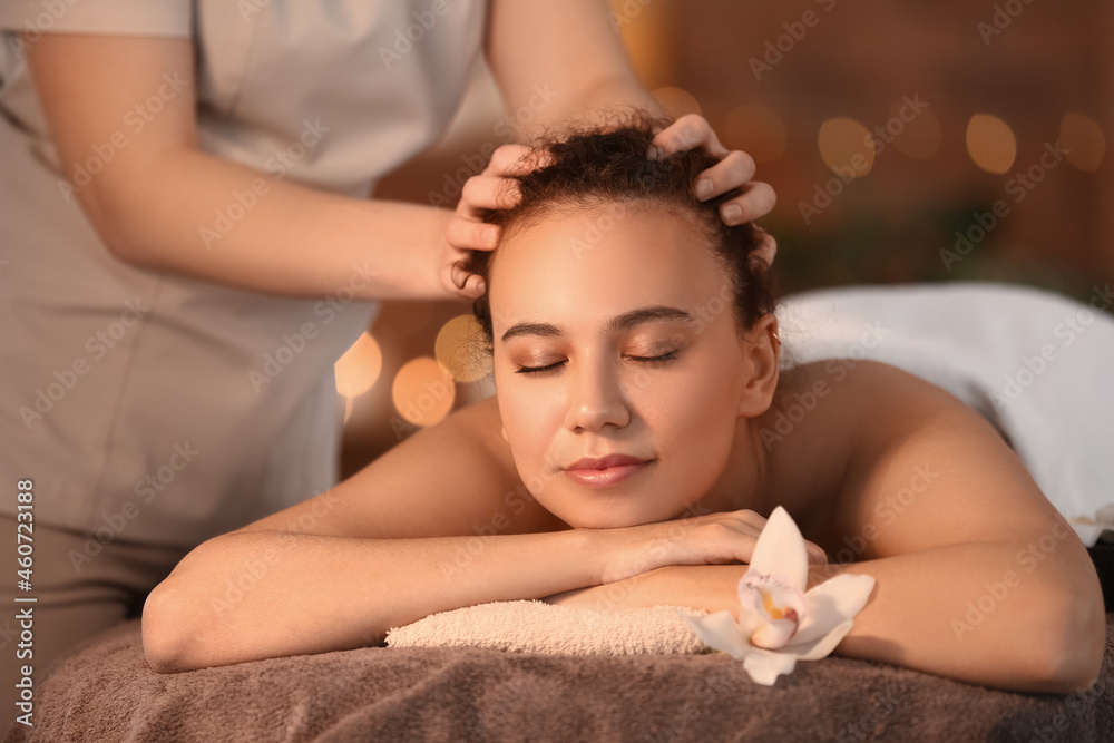 Beautiful young African-American woman getting massage in spa salon