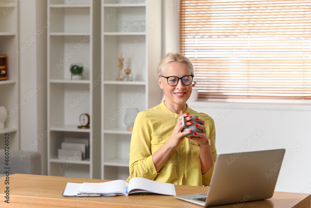 Mature woman drinking coffee in office