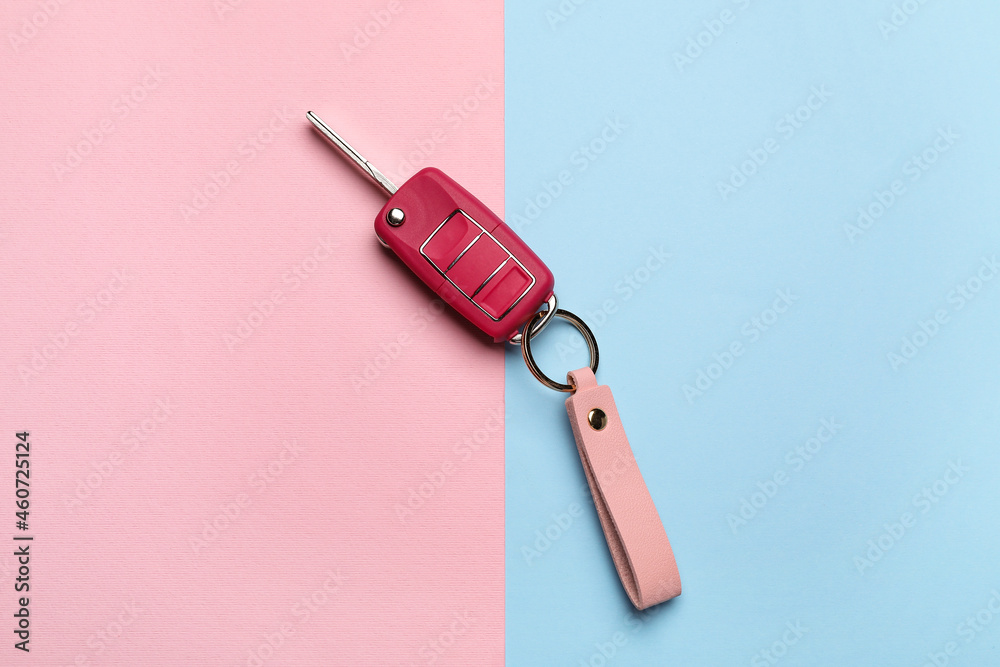 Car key with leather keychain on color background