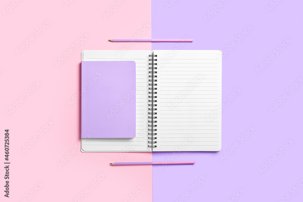 Notebooks and pencils on color background