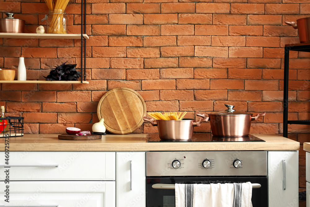 Copper cooking pots with raw spaghetti on stove in modern kitchen