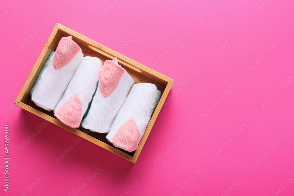 Wooden box with socks on pink background