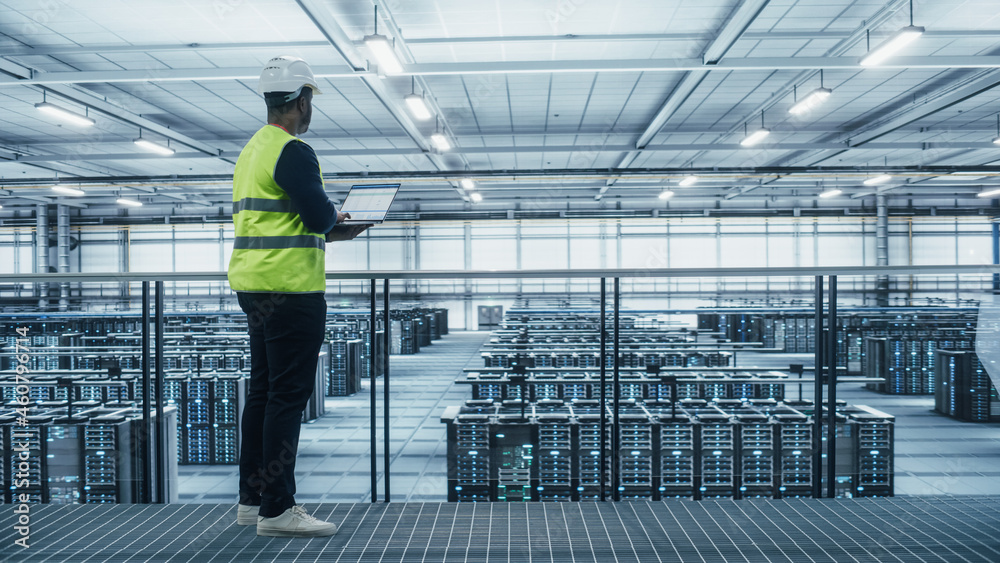 Data Center Engineer in High Visibility Vest Using Laptop Computer. Server Farm Cloud Computing Faci