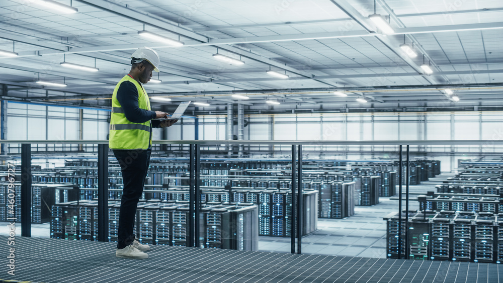 Data Center Engineer in High Visibility Vest Using Laptop Computer. Server Farm Cloud Computing Faci