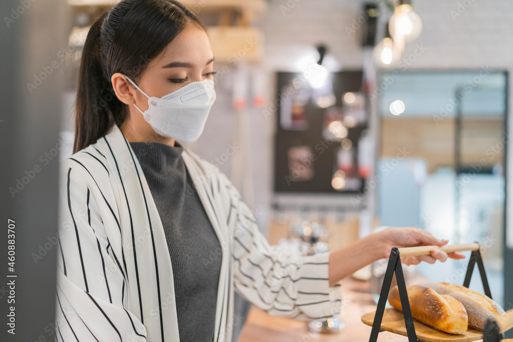 亚洲女性咖啡店老板在开小店之前预先安排面包篮