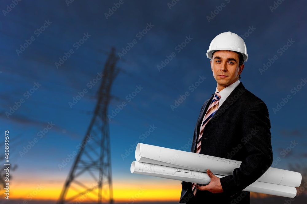 An electrician on the background of high towers of power plants looks at the project concept