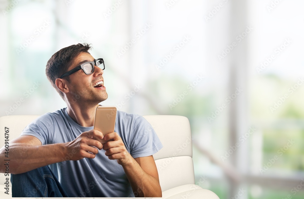 Cheerful Millennial Man Using Cellphone Browsing Internet And Texting