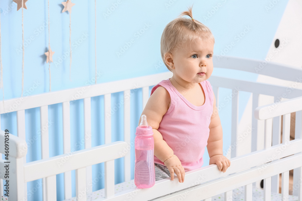 婴儿床上有一瓶水的可爱女婴