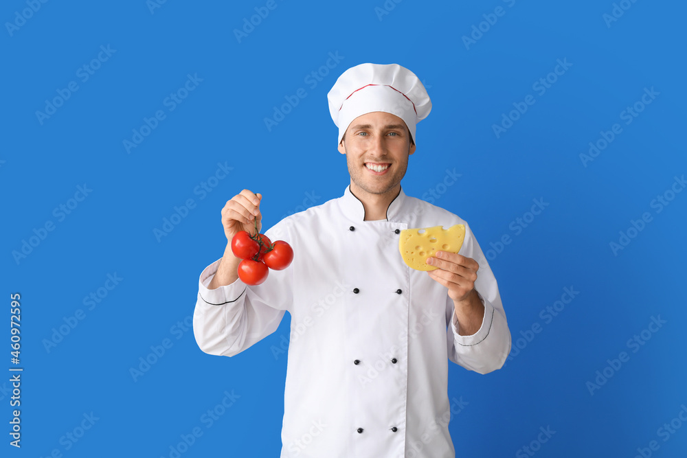 Handsome chef with fresh tomatoes and cheese on blue background