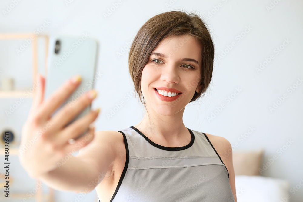 Sporty young woman taking selfie at home