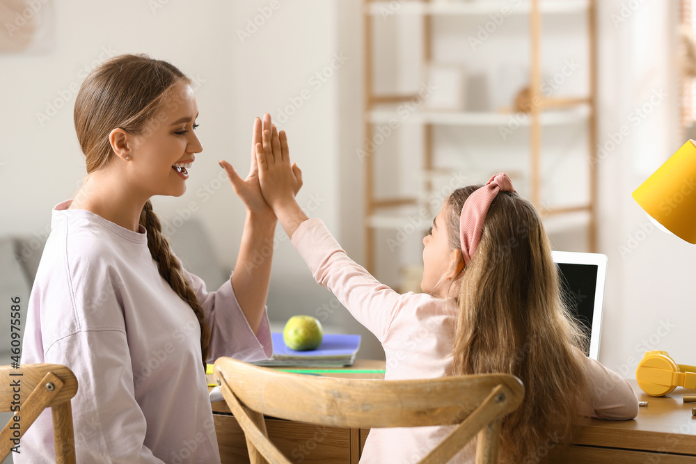 Little girl and her mother giving each other high-five at home