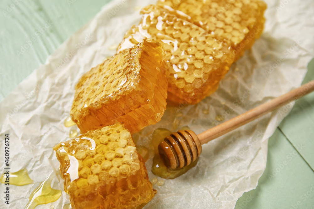 Parchment with honey combs on green wooden background, closeup