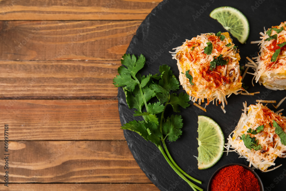 Board with pieces of tasty Elote Mexican Street Corn on wooden background, closeup