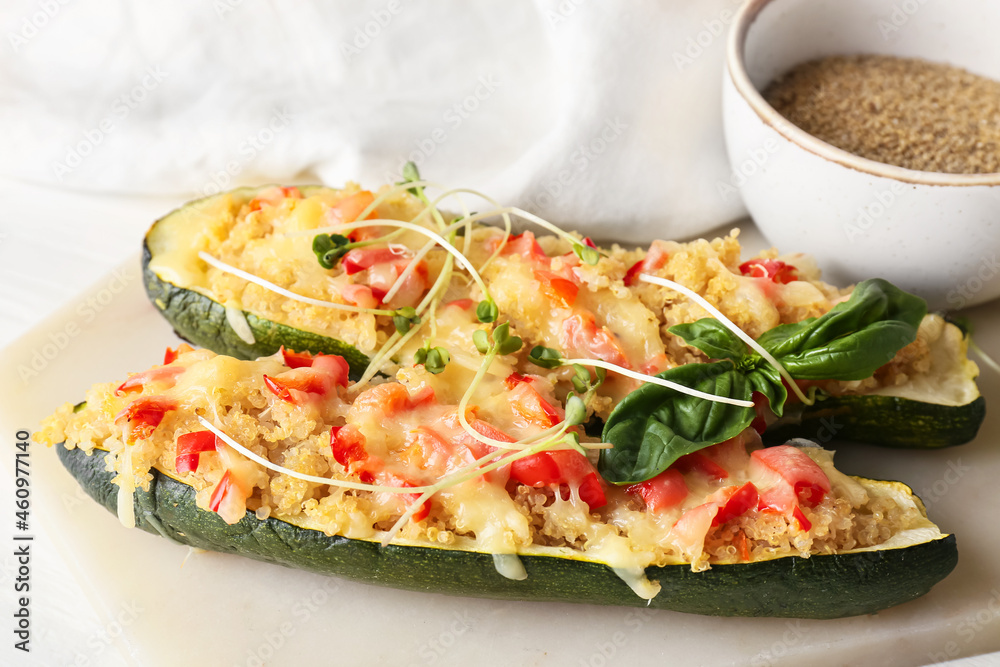 Board with quinoa stuffed zucchini boats on light background, closeup