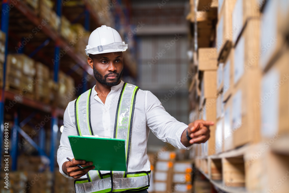 Portrait of an African warehouse manager holding a clipboard checking inventory in a large distribut