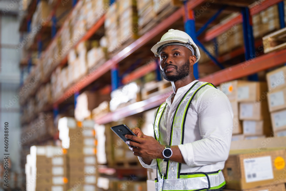 Warehouse worker working process checking the package with a tablet in a large distribution center. 